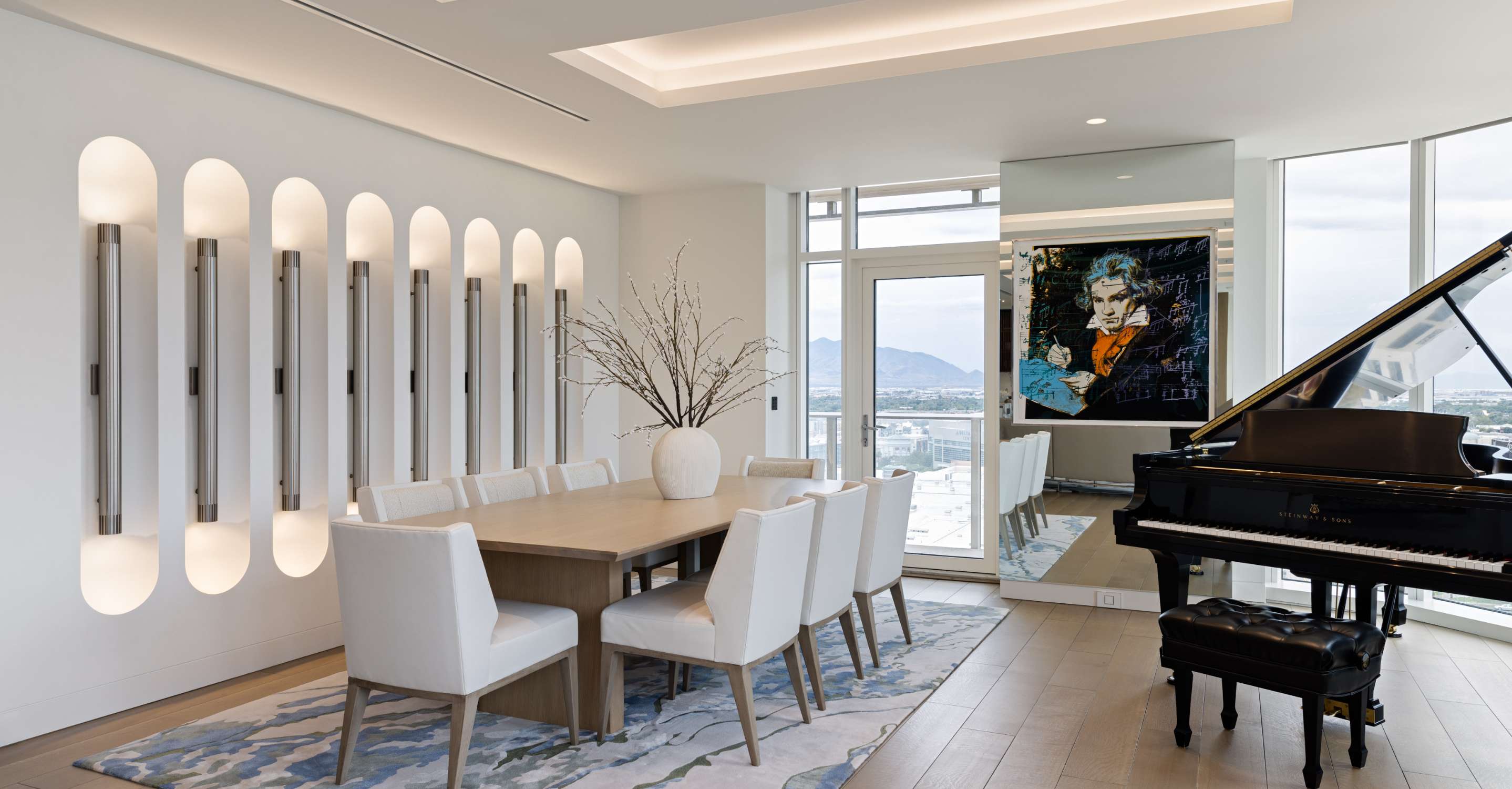 A classical-style condo dining room is shown with modernist wall-mounted lights. A baby grand piano is shown with its lid open and a Beethoven painting in a contemporary style adorns the wall.