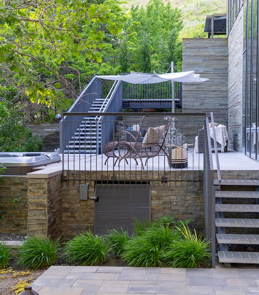 Gold wire frame chairs are shown against a kitchen bar with dining wares in front of a kitchen area with dark wood cabinetry and stainless steel appliances.